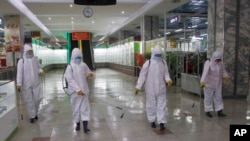 FILE - Staff of the Pyongyang Department Store No. 1 disinfect the store to help curb the spread of the coronavirus before it opens in Pyongyang, North Korea, Dec. 28, 2020.