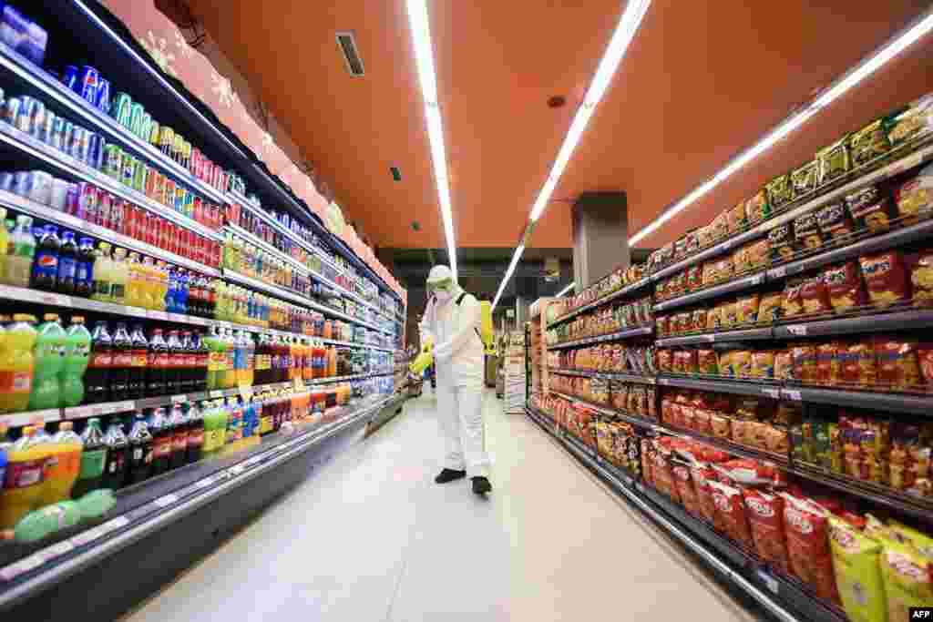 A worker disinfects the floor of a food store as a preventive measure against the spread of the new coronavirus, COVID-19, in Pristina, Kosovo.