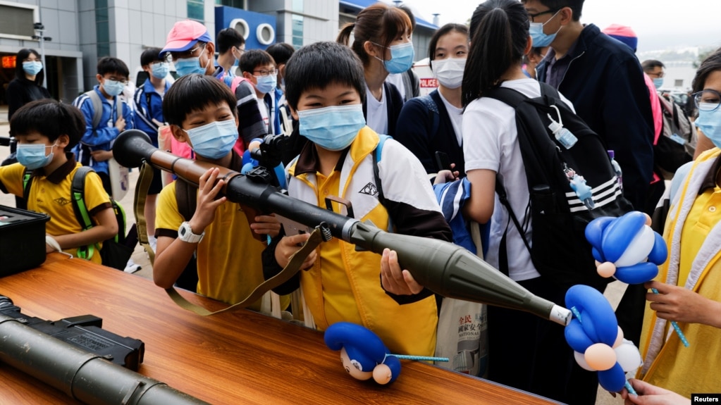 香港小学生在2021年4月15日的“全民国家安全教育日”展览上拿起仿造的榴弹发射器