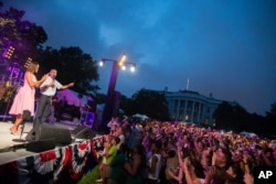 President Barack Obama, accompanied by first lady Michelle Obama, delivers remarks during an Independence Day celebration on the South Lawn at the White House in Washington, July 4, 2015.