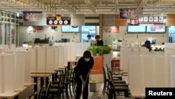 2022 年 1 月 11 日，香港為控制新冠病毒感染而暫停晚市服務後，一名餐廳職員在空蕩蕩的美食廣場擦拭地板 (路透社照片) 