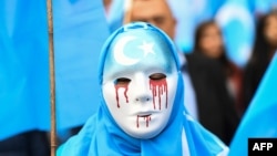A person wearing a white mask with tears of blood takes part in a protest march of ethnic Uighurs during a demonstration around the EU institutions in Brussels.