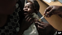 A mother holds her baby as she receives a new malaria vaccine at the Walter Reed Project Research Center in Kenya, October 30, 2009. 