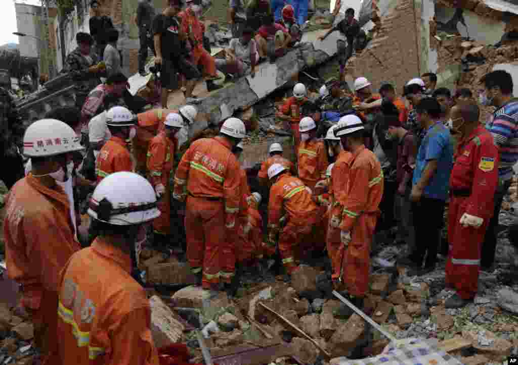 Rescuers try to retrieve a trapped victim&#39;s body from a collapsed house following a massive earthquake in the town of Longtoushan in Ludian County in southwest China&#39;s Yunnan Province, Aug. 5, 2014.