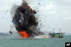 FILE - Debris flies into the air as foreign fishing boats are blown up, Feb. 22, 2016, by the Indonesian Navy off Batam Island, Indonesia.