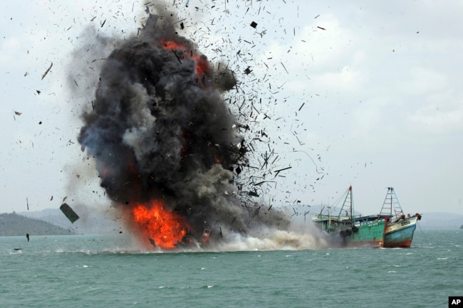 FILE - Debris flies into the air as illegal fishing boats are blown up, Feb. 22, 2016, by the Indonesian Navy off Batam Island, Indonesia. Blowing up illegal vessels has become somewhat of a local tourist attraction in Indonesia.