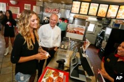 Sports Illustrated swimsuit model Hannah Ferguson, left, orders lunch along side CKE Restaurants CEO Andy Puzder after a news conference on Aug. 6, 2014 in Austin, Texas
