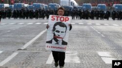 یکی از معترضان تصویر امانوئل ماکرون را در جریان اعترضات در پاریس حمل می کند.