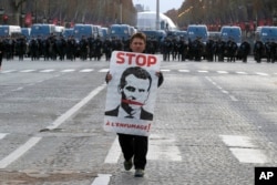 Demonstrant nosi sliku francuskog predsednika Makrona sa potpisom "Zaustavite obmane" na protestu na Šanzelizeu u subotu, 8. decembra 2018.