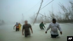 Voluntarios caminan bajo el viento y la lluvia del huracán Dorian en Freeport, Grand Bahama, Bahamas, el martes, 3 de septiembre de 2019.