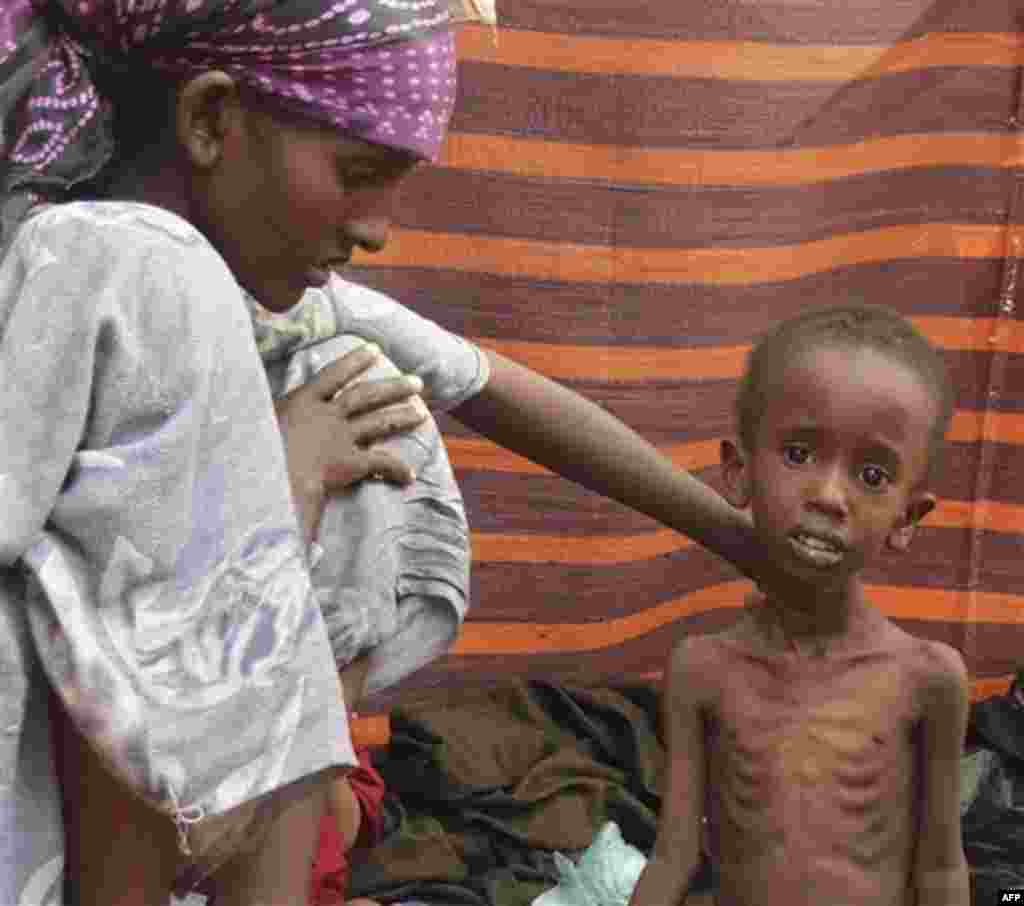A refugee woman from southern Somalia, attends to her child in their makeshift shelter in a refugee camp in Mogadishu, Somalia, Saturday, Aug. 6, 2011. The United Nations predicts that famine will probably spread to all of southern Somalia within a month