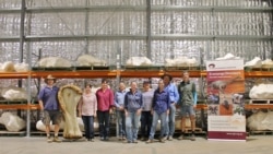 Research team poses with a bone from "Cooper" (Eromanga Natural History Museum/Handout via Reuters)