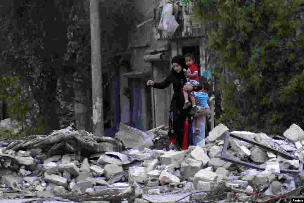 A woman carries her child as she walks on rubble in a neighbourhood in Deir al-Zor, Syria, April 15, 2013. 