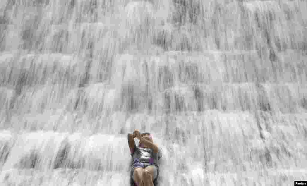 A woman enjoys the water overflowing from a defunct but still watery reservoir called the Wawa Dam in Montalban in Manila, the Philippines.