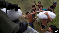 지난 11월 태풍 하이옌 피해 지역 주민들이 미 해군 소속 헬기에서 나눠주는 구호물자를 받고 있다.
