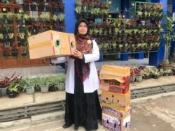 Guru SMPN 46 Bandung, Suhartini, menunjukkan kandang-kandang ayam karya siswa yang akan digunakan untuk memelihara anak ayam. (VOA/Rio Tuasikal)