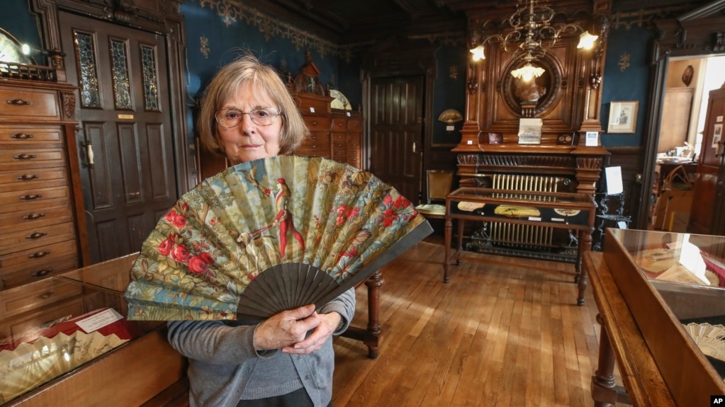 Anne Hoguet, 74, fan maker and director of the hand fan-making museum poses with a a wood roasted hand fan representing the falcon hunt, gouache painting on paper dated from 1880 in Paris, Wednesday, Jan. 20, 2021. (AP Photo/Michel Euler)