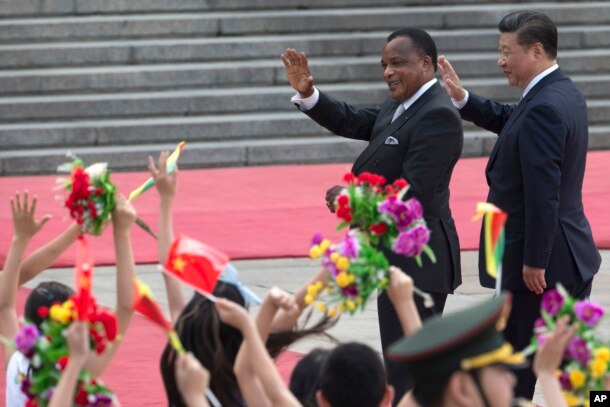 FILE - Chinese President Xi Jinping, right and Republic of Congo President Denis Sassou Nguesso wave as they walk past Chinese children waving flags and flowers to welcome them at a welcome ceremony held outside the Great Hall of the People in Beijing, China, July 5, 2016.