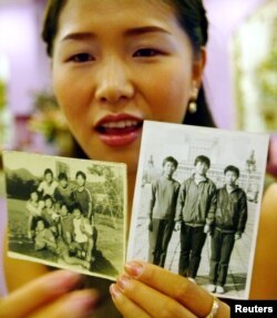FILE - North Korean defector Hwangbo Young shows pictures of her friends taken in North Korea, June 17, 2003, in Seoul, South Korea. Hwangbo, 24, a promising teenage ice hockey player, escaped North Korea's economic spiral in 1997 to settle with her family in South Korea.