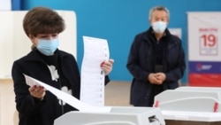 A woman casts her ballots at a polling station on the last day of three-day long parliamentary elections in Moscow, Russia, Sept. 19, 2021.