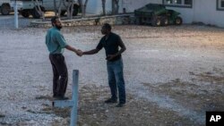 One of the managers of the Christian Aid Ministries headquarters, left, shakes hands with a worker at the center in Titanyen, north of Port-au-Prince, Haiti, Sunday, Nov. 21, 2021. (AP Photo/Odelyn Joseph)