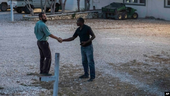 One of the managers of the Christian Aid Ministries headquarters, left, shakes hands with a worker at the center in Titanyen, north of Port-au-Prince, Haiti, Sunday, Nov. 21, 2021. (AP Photo/Odelyn Joseph)