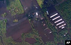 En esta foto aérea tomada el 18 de septiembre de 2018 y publicada por la Administración Nacional Oceánica y Atmosférica, se ve un sitio industrial y una granja de pollos a las afueras de Wallace, Carolina del Norte, que ha sido inundada por el cercano noreste del río Fear River luego del huracán Florence.