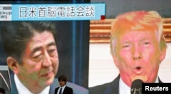 A man walks past a street monitor showing Japan's Prime Minister Shinzo Abe (L) and U.S. President Donald Trump in a news report about their telephone conference on North Korea's threat, in Tokyo, Sept. 3, 2017.