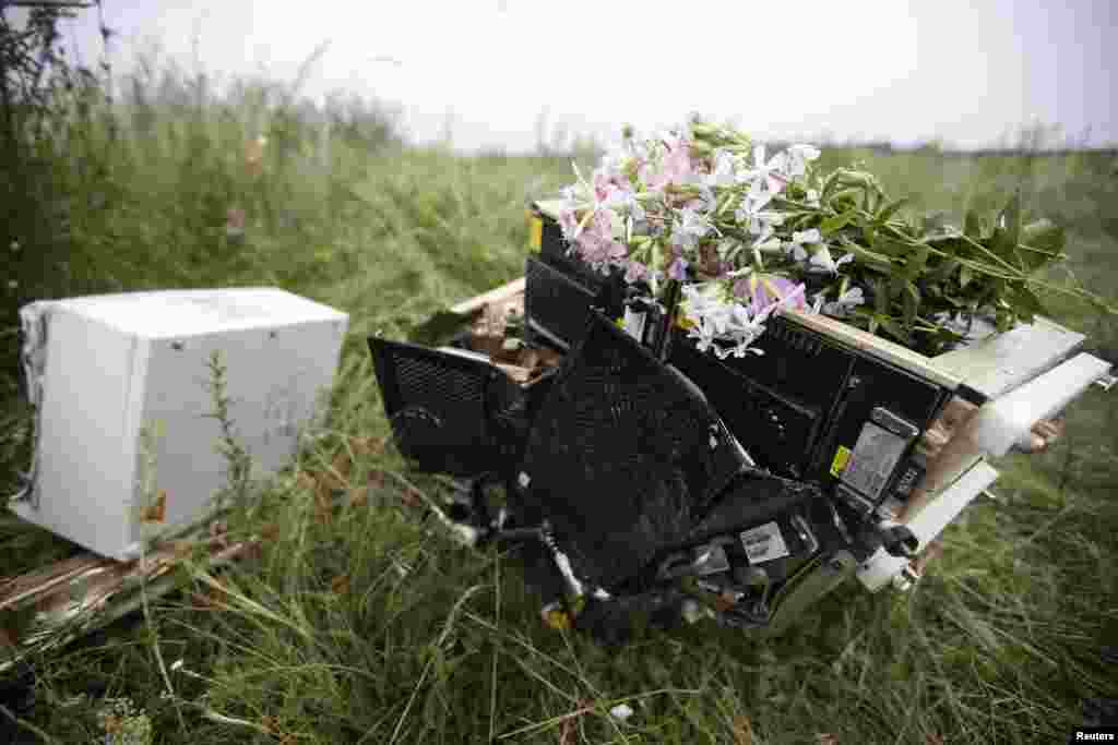 Flowers lie on debris from a Malaysian Airlines Boeing 777 plane which was downed on Thursday near the village of Rozsypne, in the Donetsk region, Ukraine.