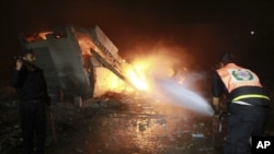 A Palestinian firefighter tries to extinguish a fire following an Israeli airstrike on a building in Gaza City, early Saturday, June 23, 2012.