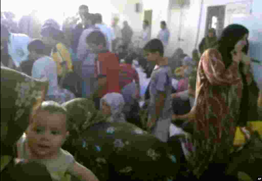This image made from amateur video from Hama Revolution 2011purports to show families gathered around bodies of victims killed in Tremseh, Syria, July 13, 2012.