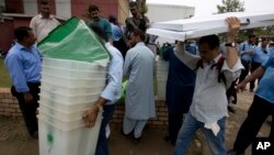 Pakistani election staff carry polling material to stations at a distribution center in Islamabad, Pakistan, July 24, 2018. 
