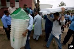 Pakistani election staff carry polling material to stations at a distribution center in Islamabad, Pakistan, July 24, 2018.