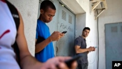 Students gather behind a business looking for a Internet signal for their smart phones in Havana, Cuba, April 1, 2014. 