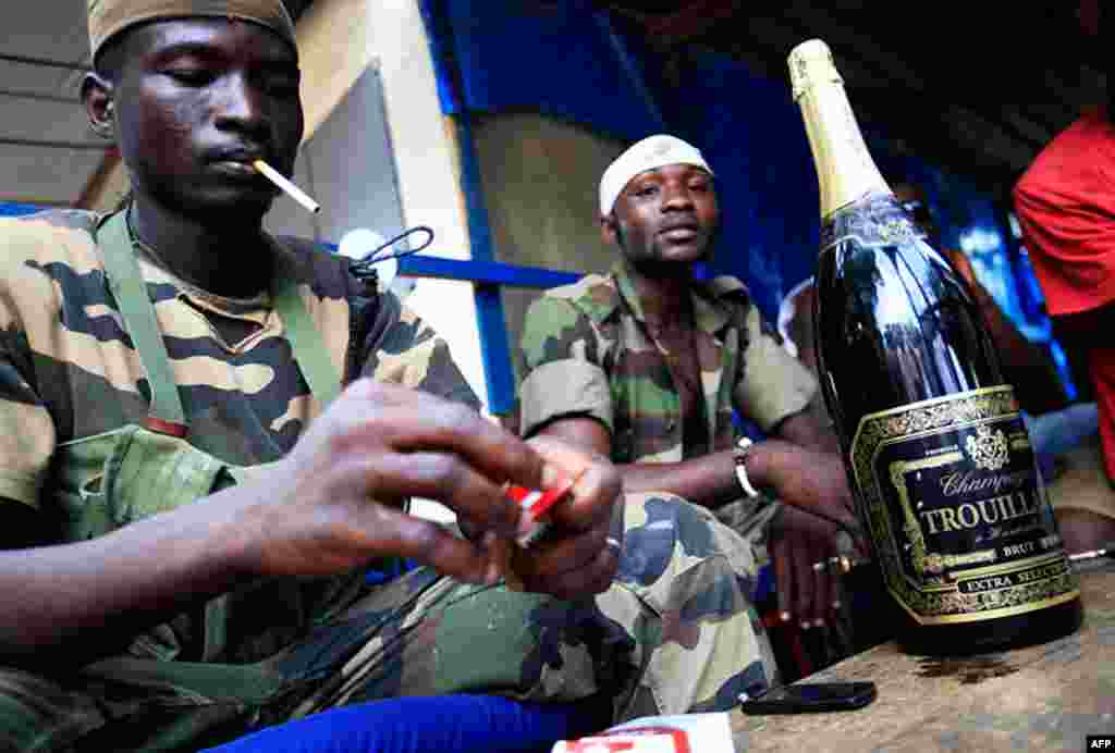 April 12: Republican forces soldiers in Ivory Coast relax around a bottle of champagne taken from the presidential residence. (AP Photo/Rebecca Blackwell)