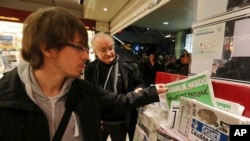 A man picks up a copy of Charlie Hebdo newspaper at a newsstand in Rennes, western France, Jan. 14, 2015.