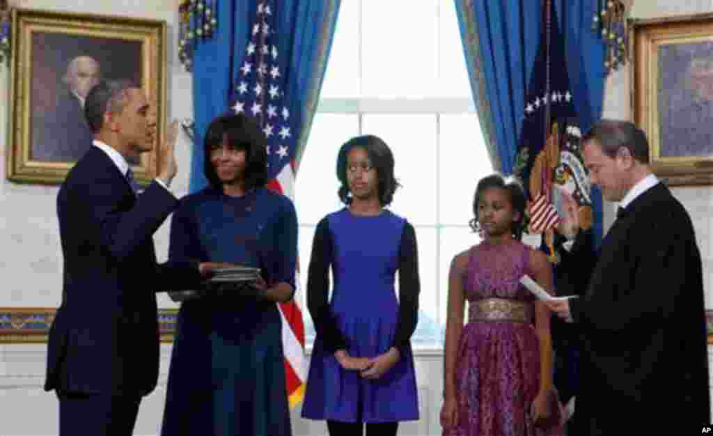 President Barack Obama takes the oath of office at the official swearing-in ceremony in the Blue Room of the White House in Washington, DC, Sunday, Jan. 20, 2013, holding the family bible is First Lady Michele Obama, administering the oath is Supreme Cour