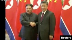 North Korean leader Kim Jong Un shakes hands with Chinese President Xi Jinping, in this still image taken from video released March 28, 2018. 