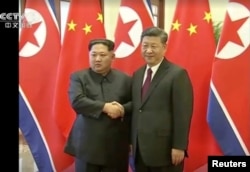 North Korean leader Kim Jong Un shakes hands with Chinese President Xi Jinping, in this still image taken from video released March 28, 2018.