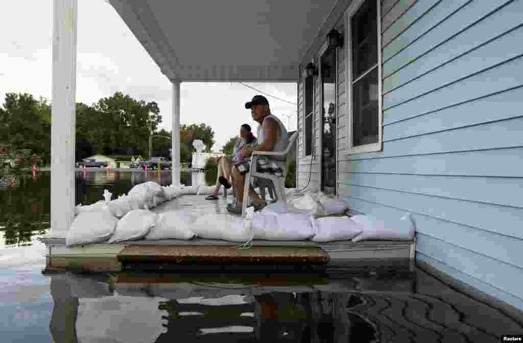 Megan Schexnayder et David McNeely sont assis sur leur porche encerclé par les eaux à Sorrento, Lousiane, le 17 août 2017.