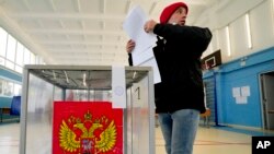 A young man casts his ballots during parliamentary and local elections, at a polling station outside St. Petersburg, Russia, Sept. 17, 2021. 