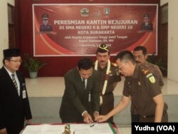 Kepala Kejaksaan Tinggi Jateng (tiga dari kiri, berkalung bunga) dan Walikota Solo (berkumis, paling kanan) menyaksikan penandatanganan MOU kantin kejujuran di sekolah. (Foto: VOA/Yudha)