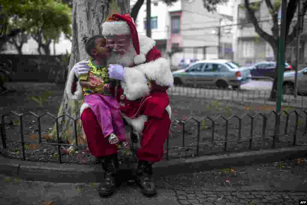 브라질 리우데자네이루의 산타클로스 학교에서 성탄 시즌 종료를 축하하는 동창회가 열렸다. 한 전문 산타클로스가 소녀와 함께 기념촬영을 하고 있다.
