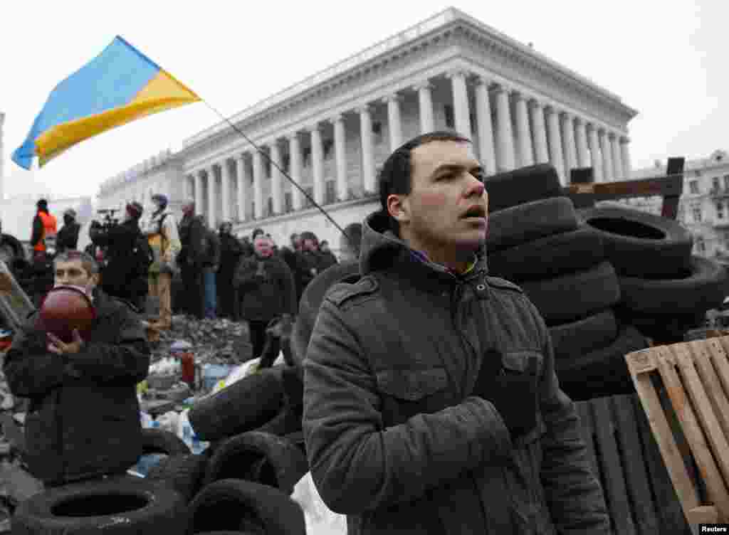 Người biểu tình chống chính phủ hát quốc ca trong lúc&nbsp;tụ tập bên cạnh các chướng ngại vật tại trung tâm thủ đô Kiev, ngày 19/2/2014.