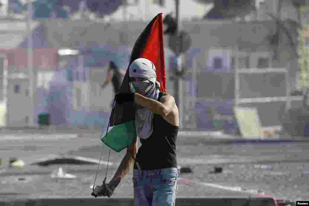 Seorang pemuda Palestina membawa bendera Palestina dalam Jumat pertama bulan Ramadhan di Shuafat, Yerusalem (4/7). (Reuters/Baz Ratner)
