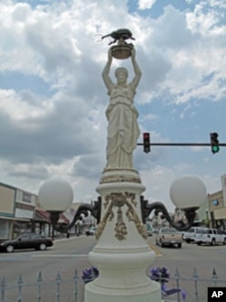A statue on Main Street in Enterprise, Alabama, features a woman holding a large, black boll weevil above her head.