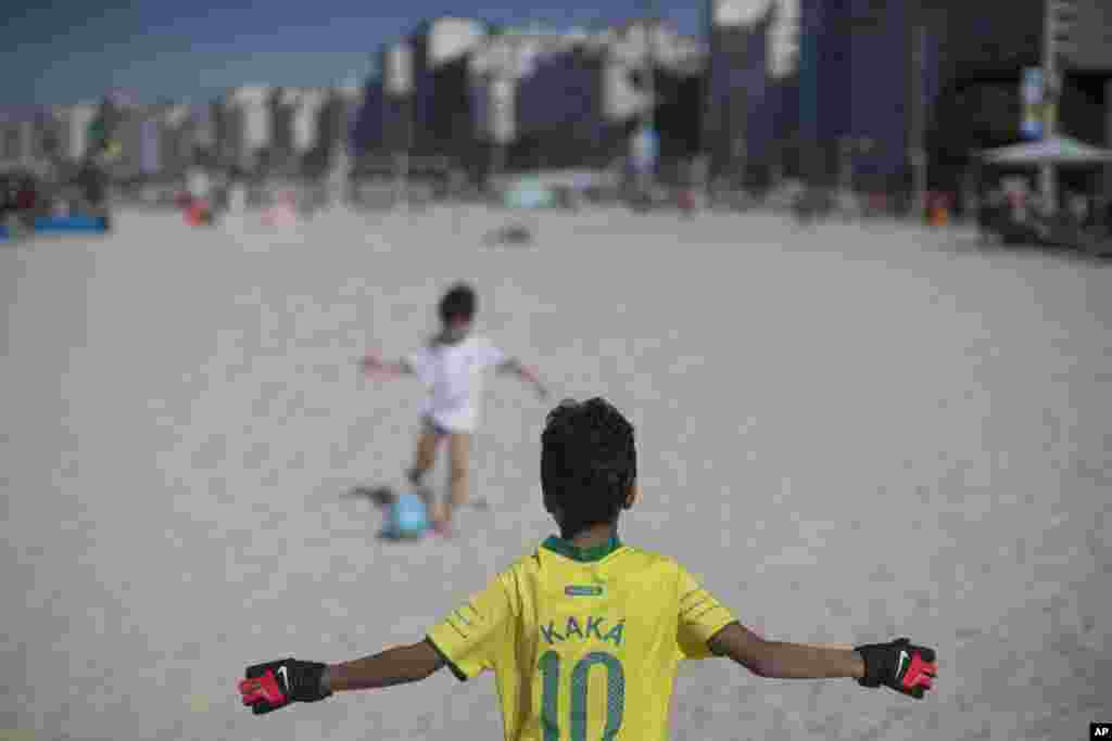 Anak-anak bermain sepakbola di pantai Copacabana di Rio de Janeiro, Brazil (8/6). (AP/Felipe Dana)