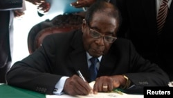 Zimbabwe President Robert Mugabe signs the country's new constitution into law in the capital Harare, replacing a 33-year-old document forged in the dying days of British colonial rule and paving the way for elections later this year, May 22, 2013.