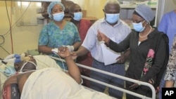 UN Deputy Secretary-General Asha-Rose Migiro, right, gives a thumbs up symbol to an employee of the WHO injured in Friday's suicide attack on UN headquarters, as she visits victims of the blast in Abuja, Nigeria, August 28, 2011