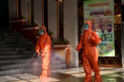 FILE - Workers spray disinfectant as part of preventative measures to curb the spread of the coronavirus at the Yokjon Department Store in Pyongyang, North Korea, Oct. 20, 2021.